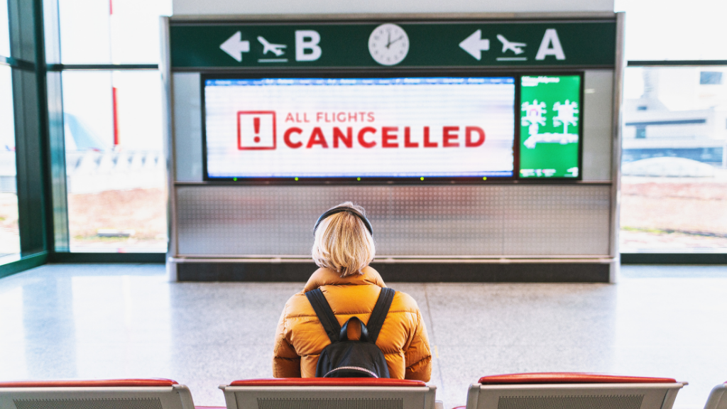 woman at airport looking at cancelled notice