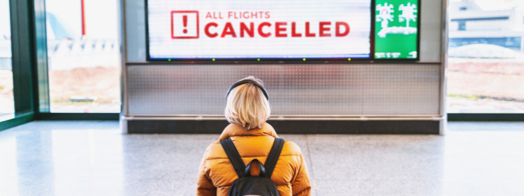 woman at airport looking at cancelled notice