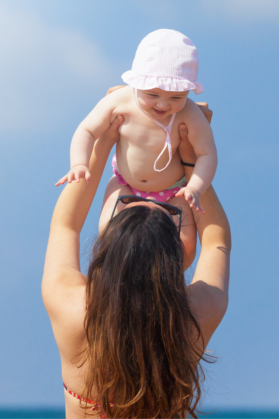 woman holding newborn baby at beach